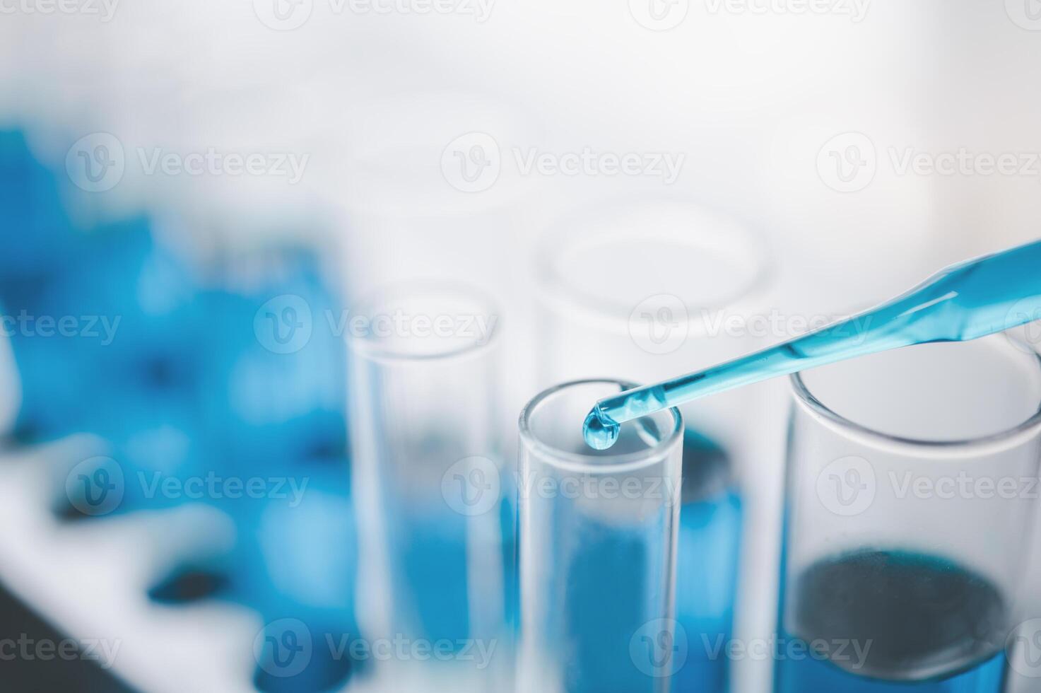 closeup-pipette dropping a sample into a test tube in an experiment research in laboratory photo