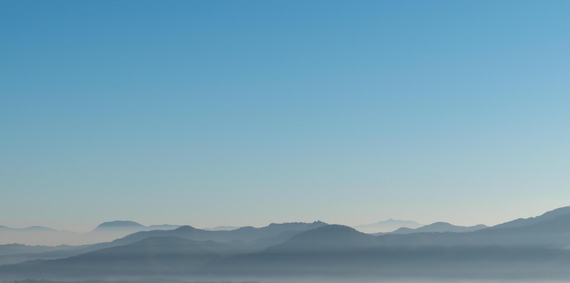 Misty wide hills landscape with blue sky negative space. photo