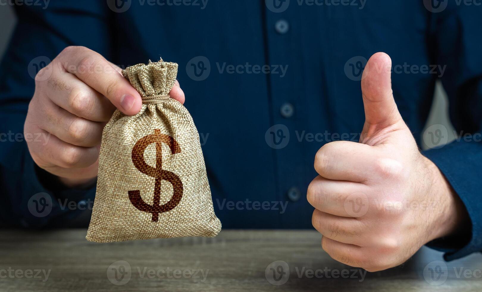 The man approves the deal or loan. Thumbs up and dollar money bag. Agreement to be hired for a job at the offered salary. Profit-generating deposits savings. photo