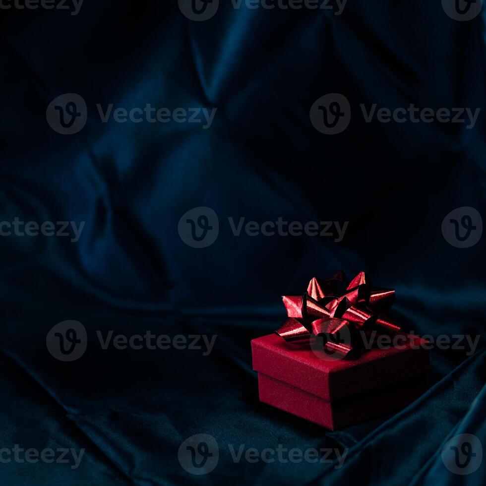 Red gift box on dark moody background. photo