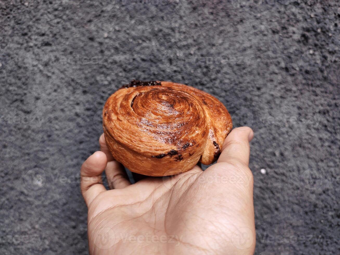 mano participación cromboloni, redondo cuerno, nuevo York rollo, un viral Pastelería combinatorio croissants y bomboloni en hormigón pared antecedentes. foto