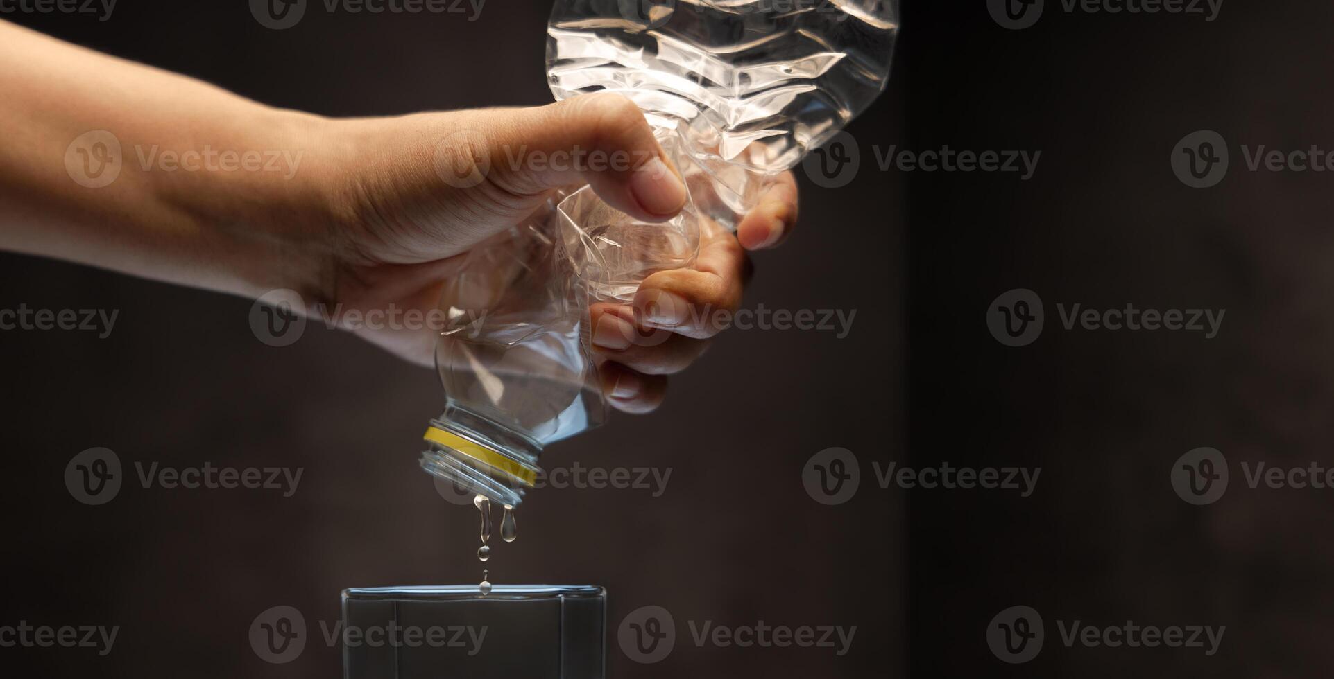 Water Crisis, Climate Change, El Nino, Global Warming Issue Concept. Hand trying to Squeeze Water from a bottle to a Glass photo