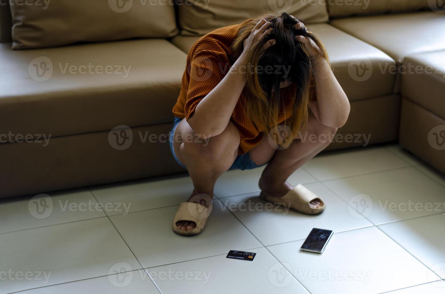 Asian woman holds her head in her hands and sits on the ground in despair after talking with a gang. Scammers and were tricked out of all their money. photo