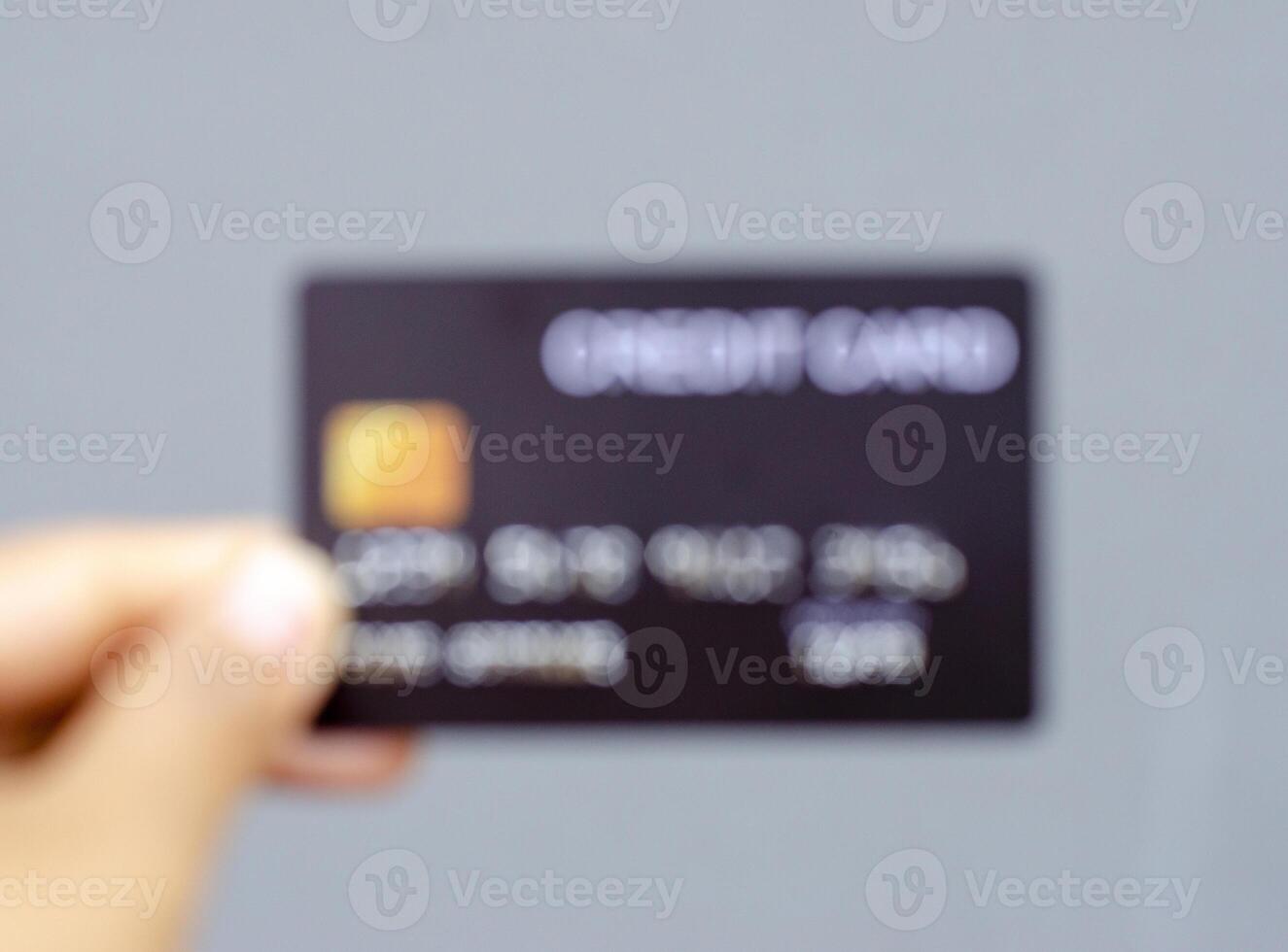 blurred background of female hand holds a black credit card mockup with security chip embedded photo