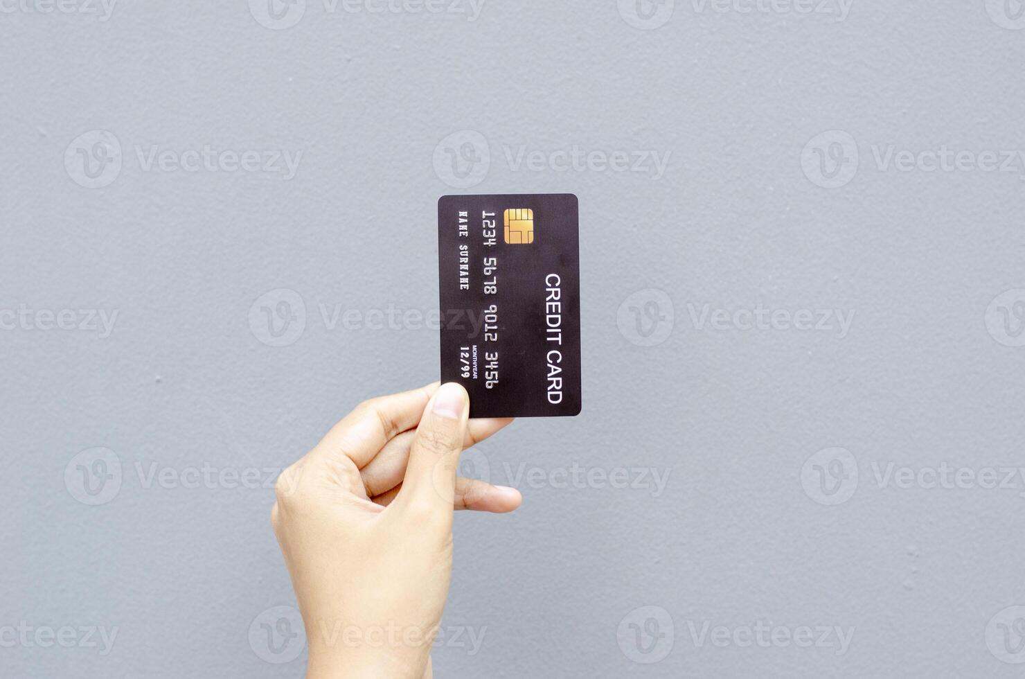 female hand holding a black credit card mockup with security chip embedded on a gray background photo