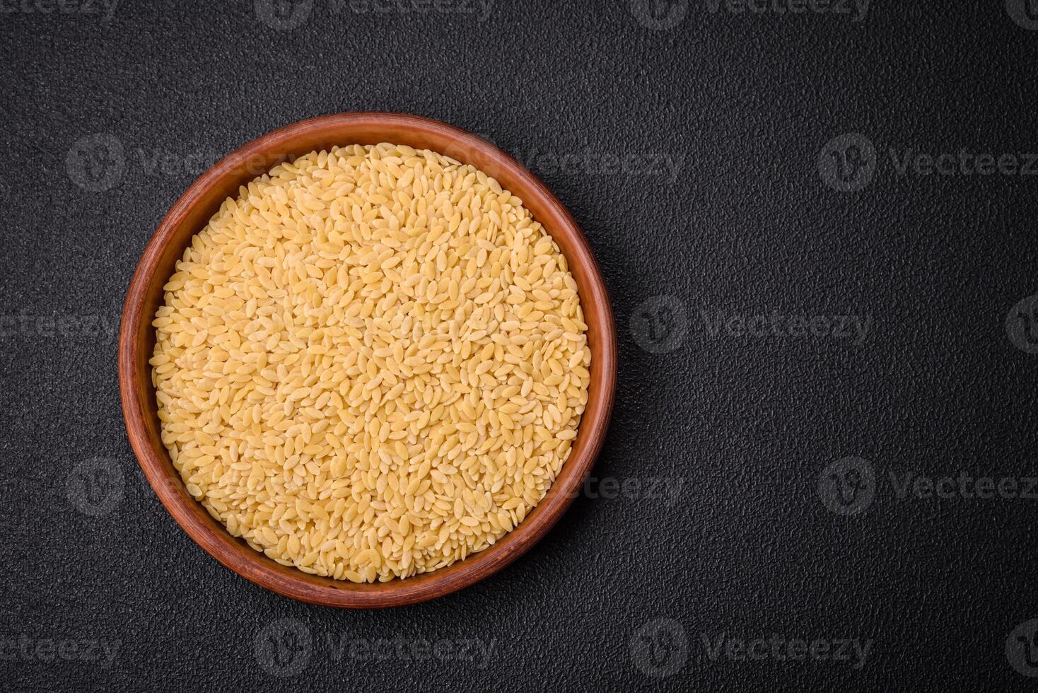 Raw risoni pasta made from durum wheat on a dark concrete background photo