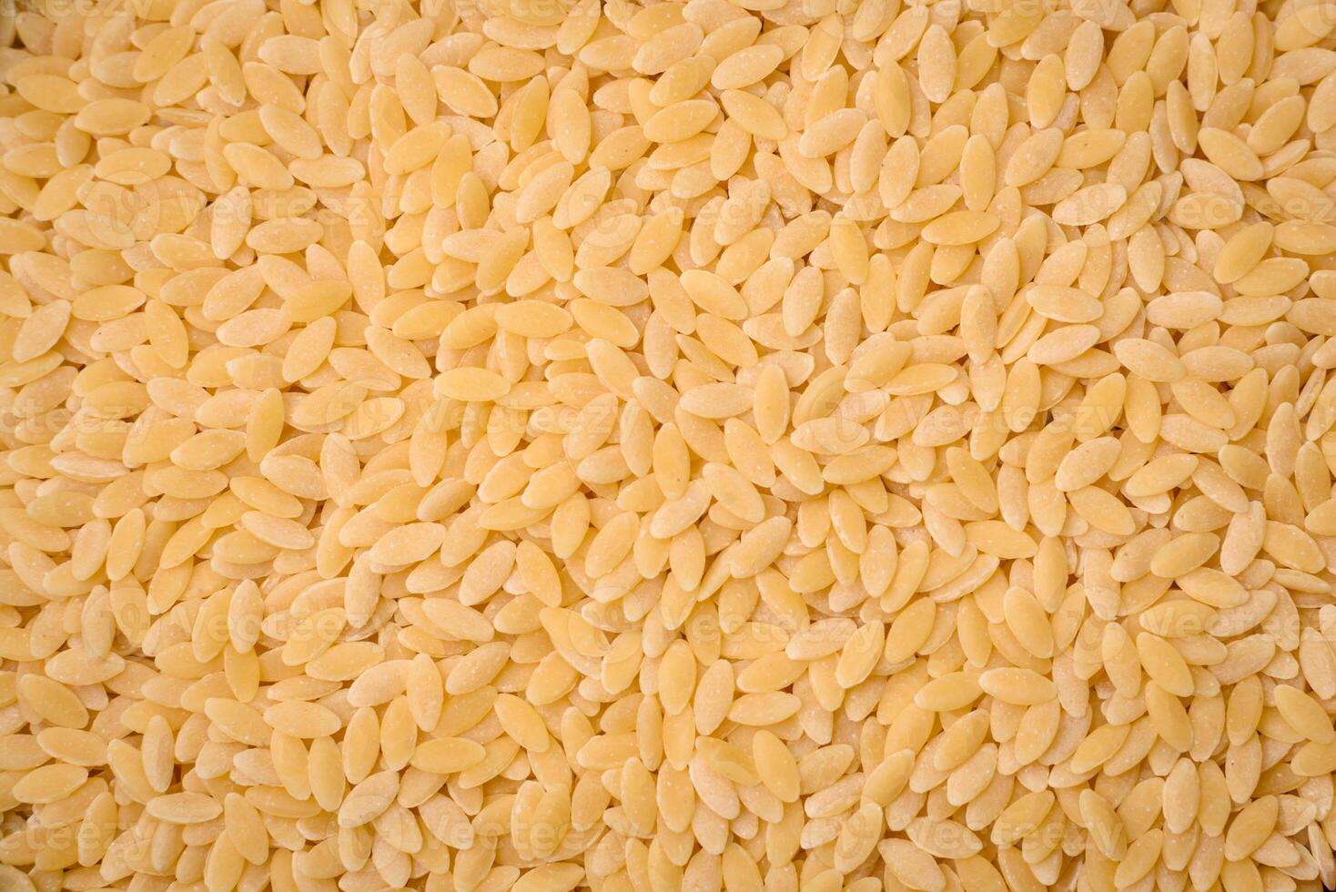 Raw risoni pasta made from durum wheat on a dark concrete background photo