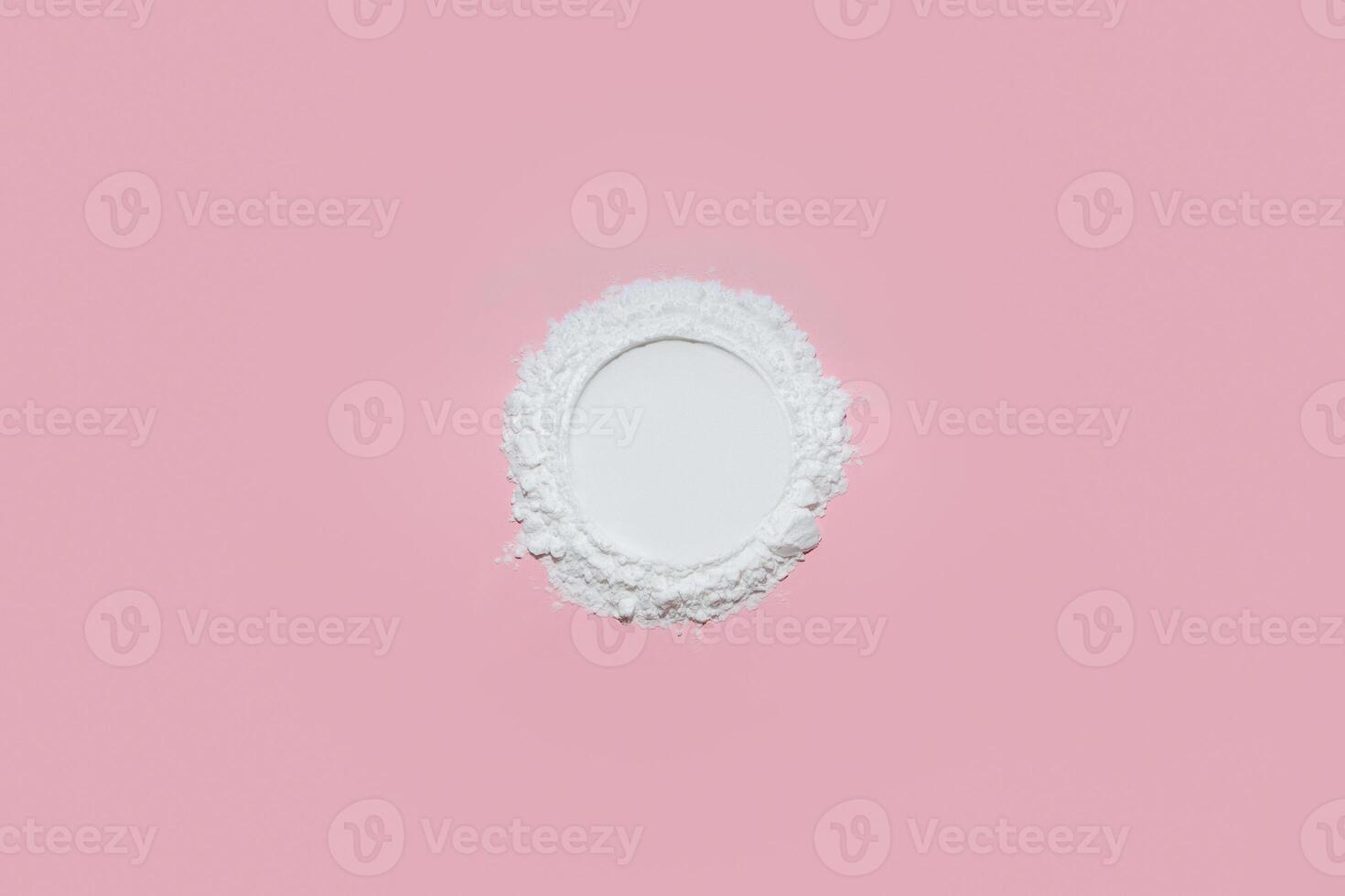 White face powder with empty circle inside on pink background photo