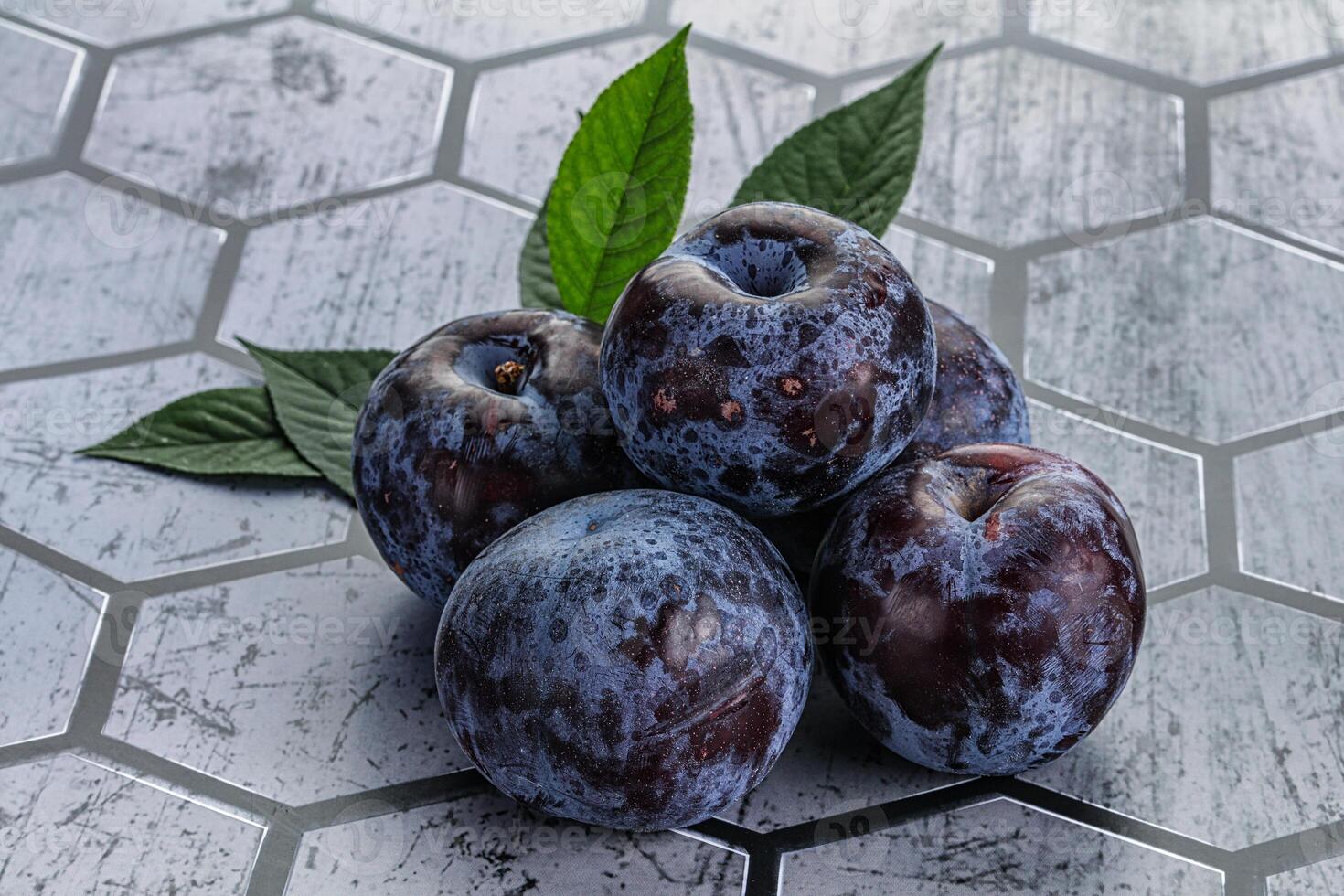 Raw purple plums heap with leaves photo