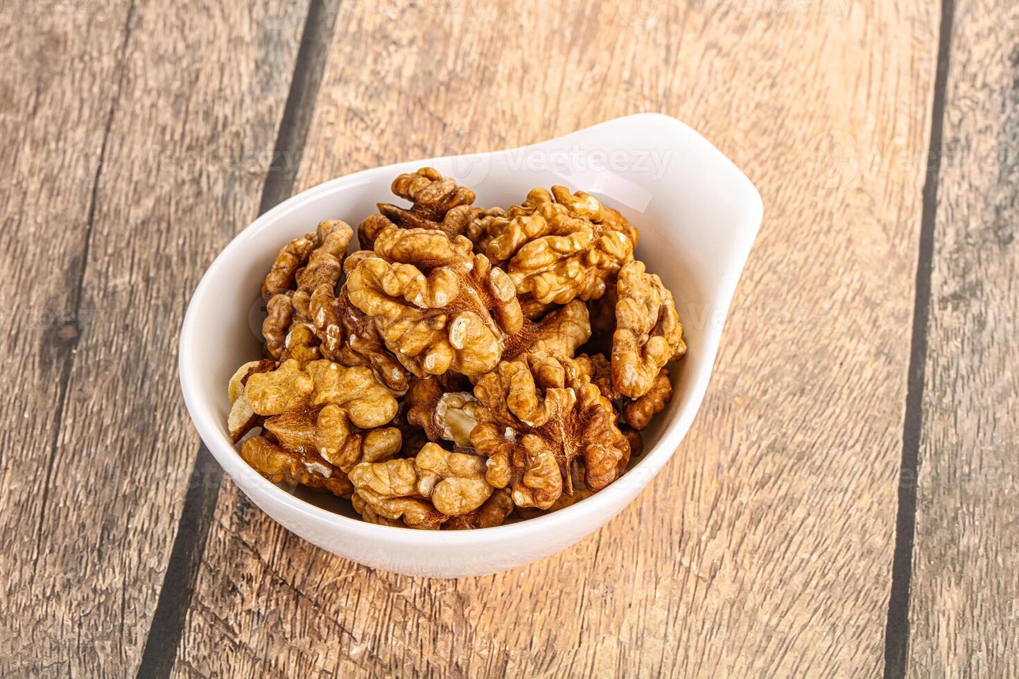 Cracked unshelled walnut in the bowl photo