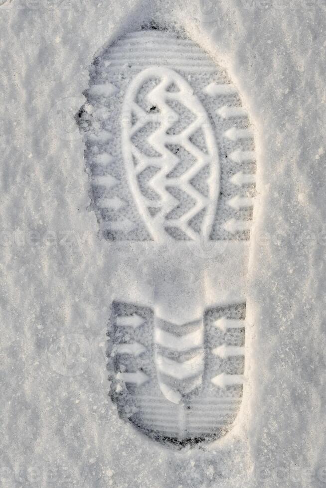 Close-up of a shoe print in the snow, top view of a boot footprint photo