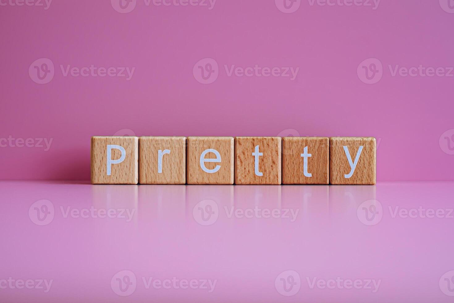 Wooden blocks form the text Pretty against a pink background. photo