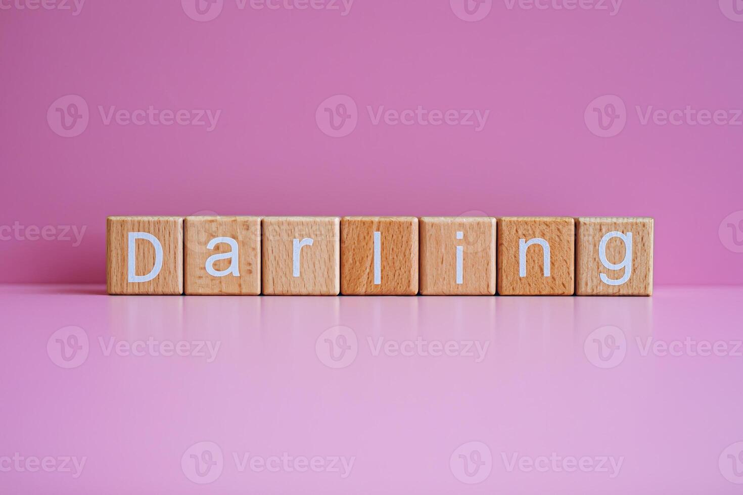 Wooden blocks form the text Darling against a pink background. photo