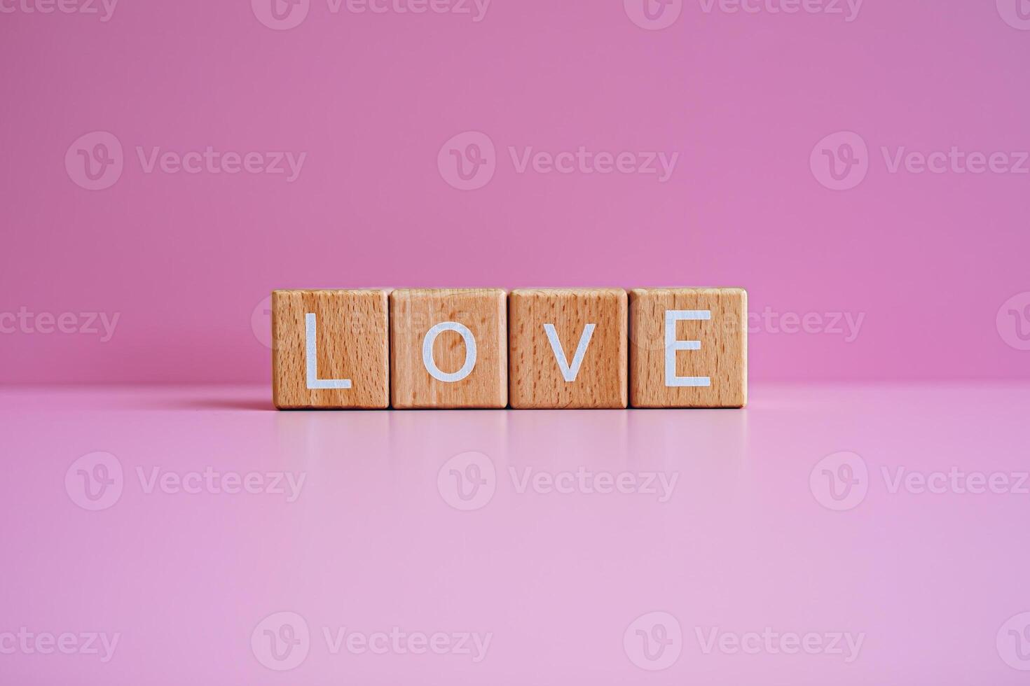 Wooden blocks form the text Love against a pink background. photo