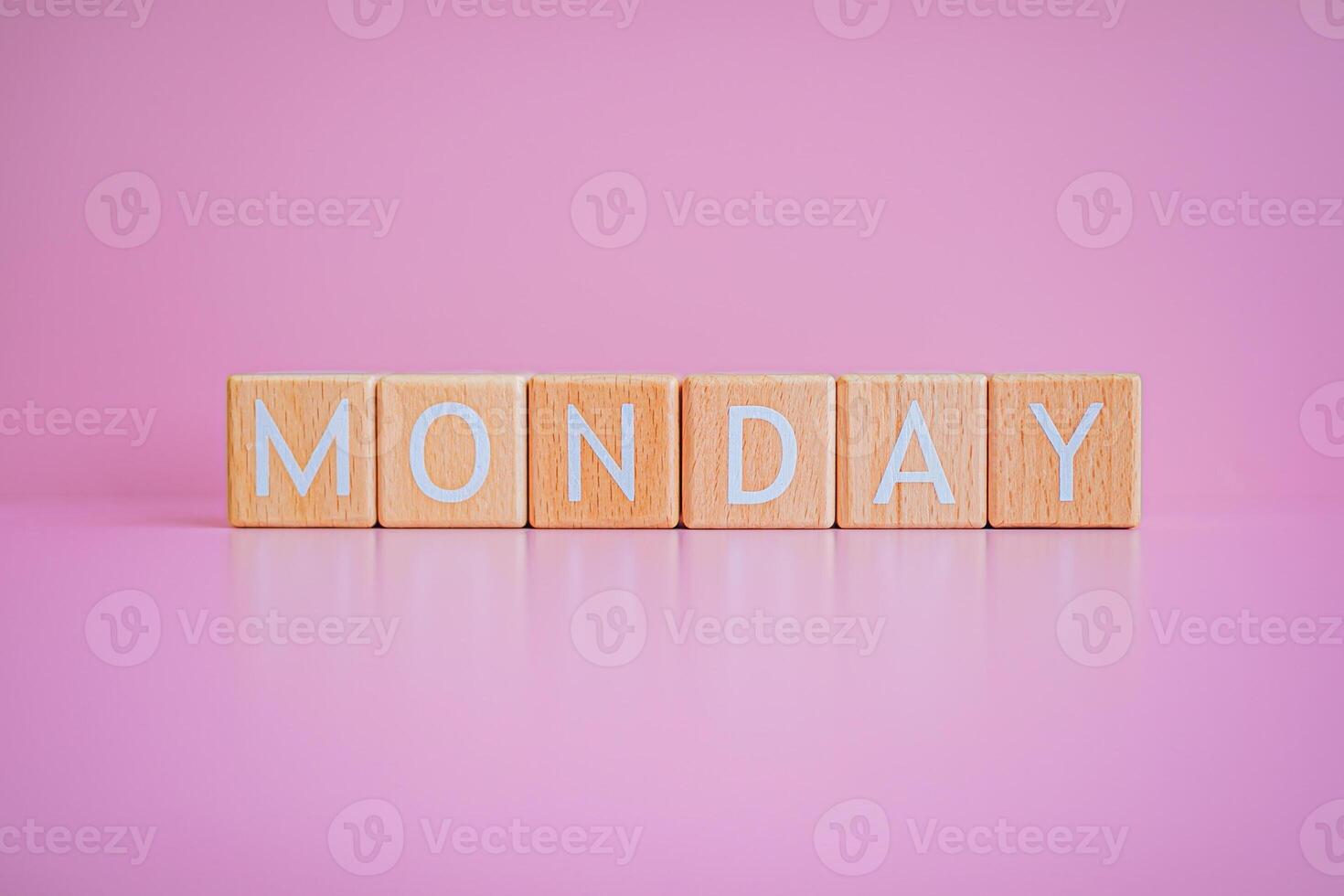 Wooden blocks form the text MONDAY against a pink background. photo