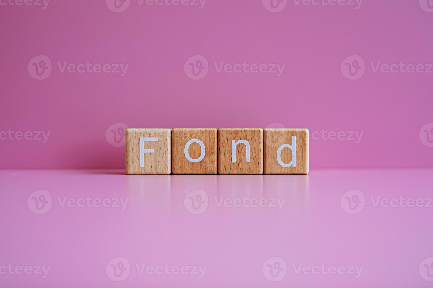 Wooden blocks form the text Fond against a pink background. photo