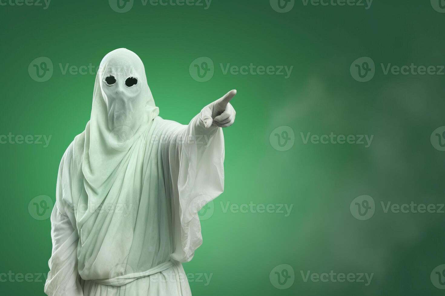 Ghost costume person pointing on green background for Halloween photo