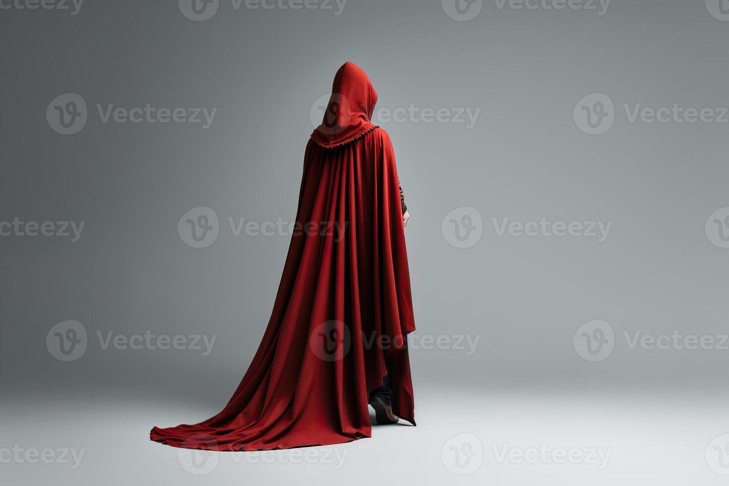 Woman in red medieval costume poses with hooded cloak photo