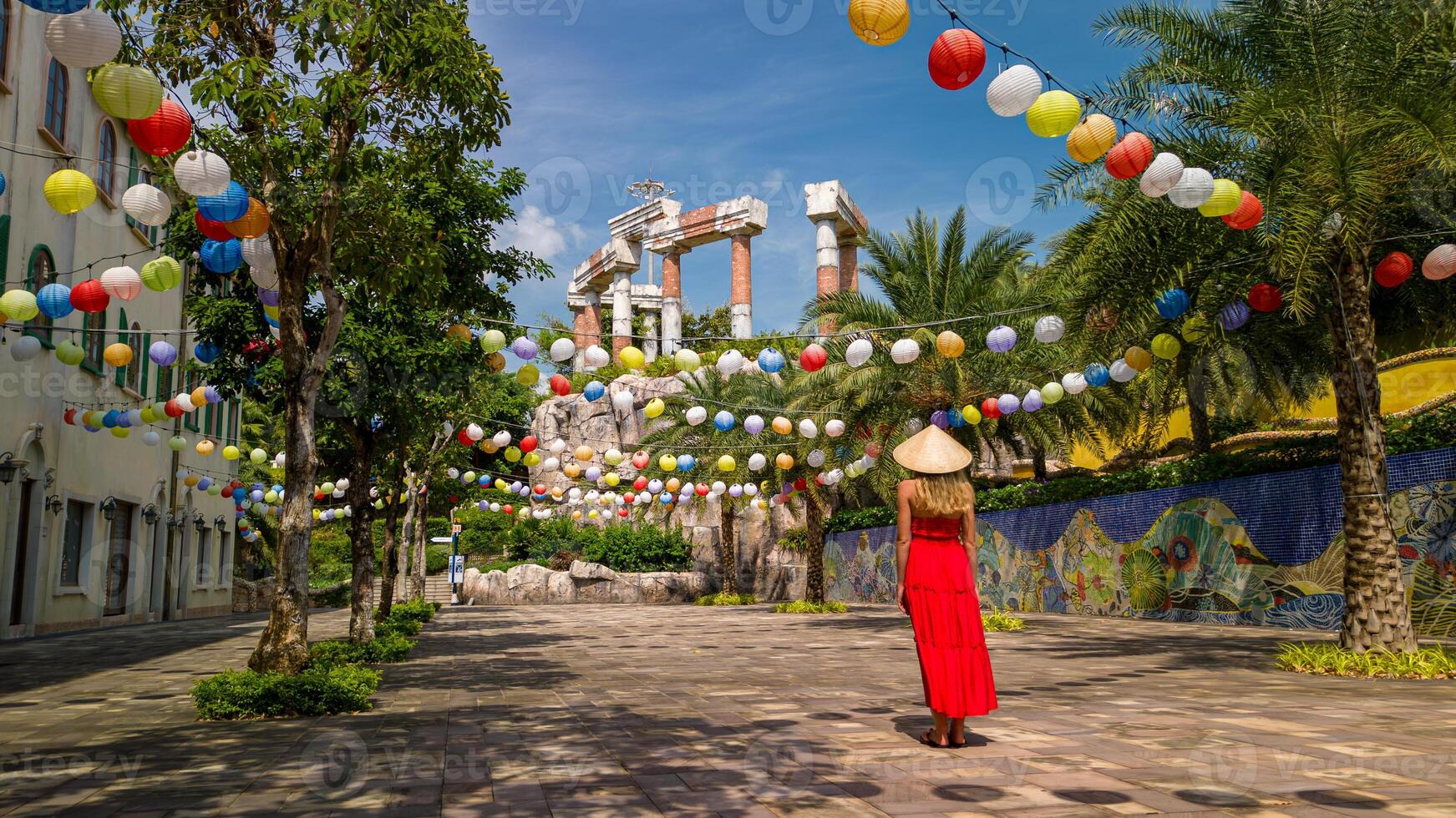 Woman in red dress and Vietnamese hat exploring Sunset Town on Phu Quoc Island photo