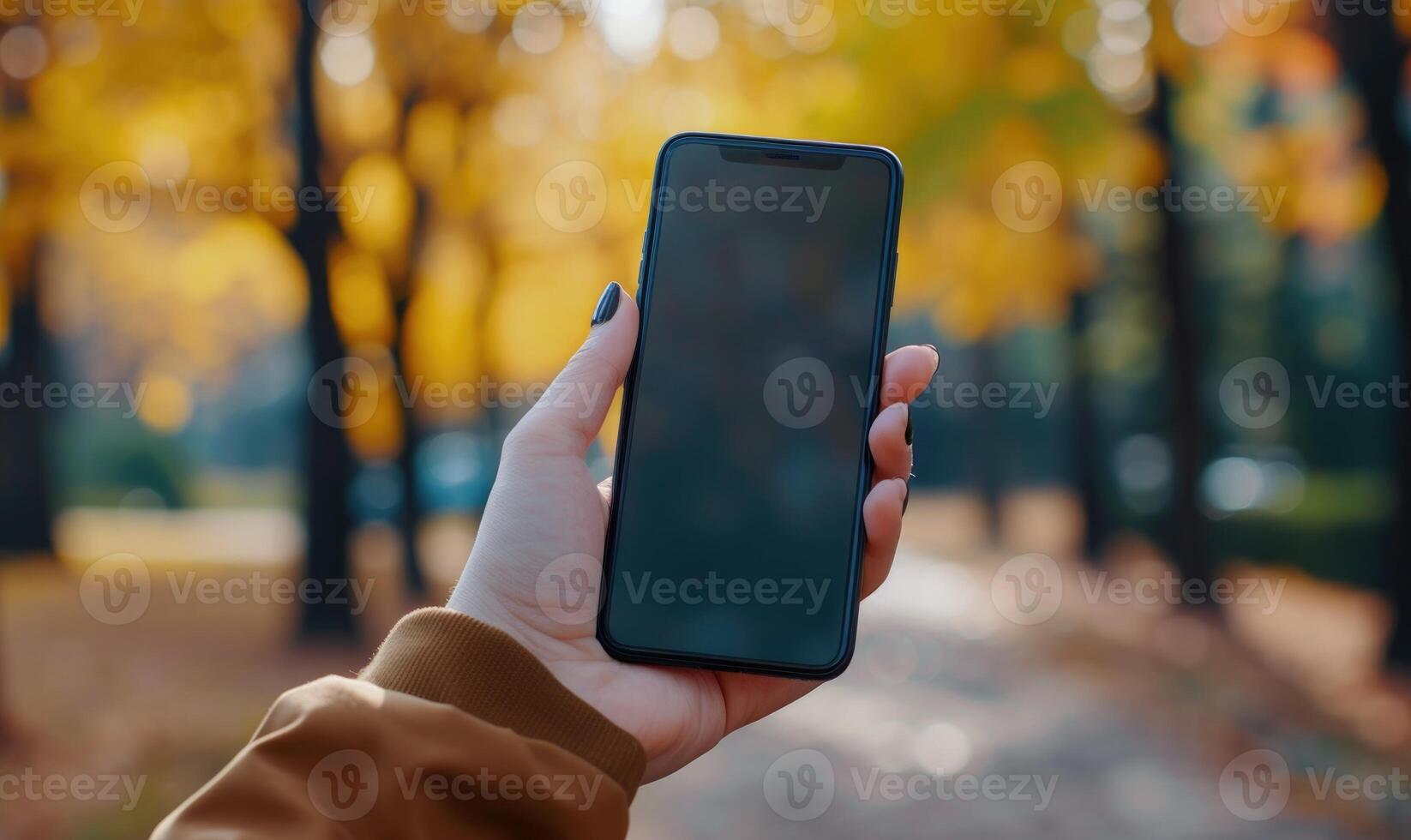 AI generated Female hand holding a smartphone with a blank screen in the autumn park photo
