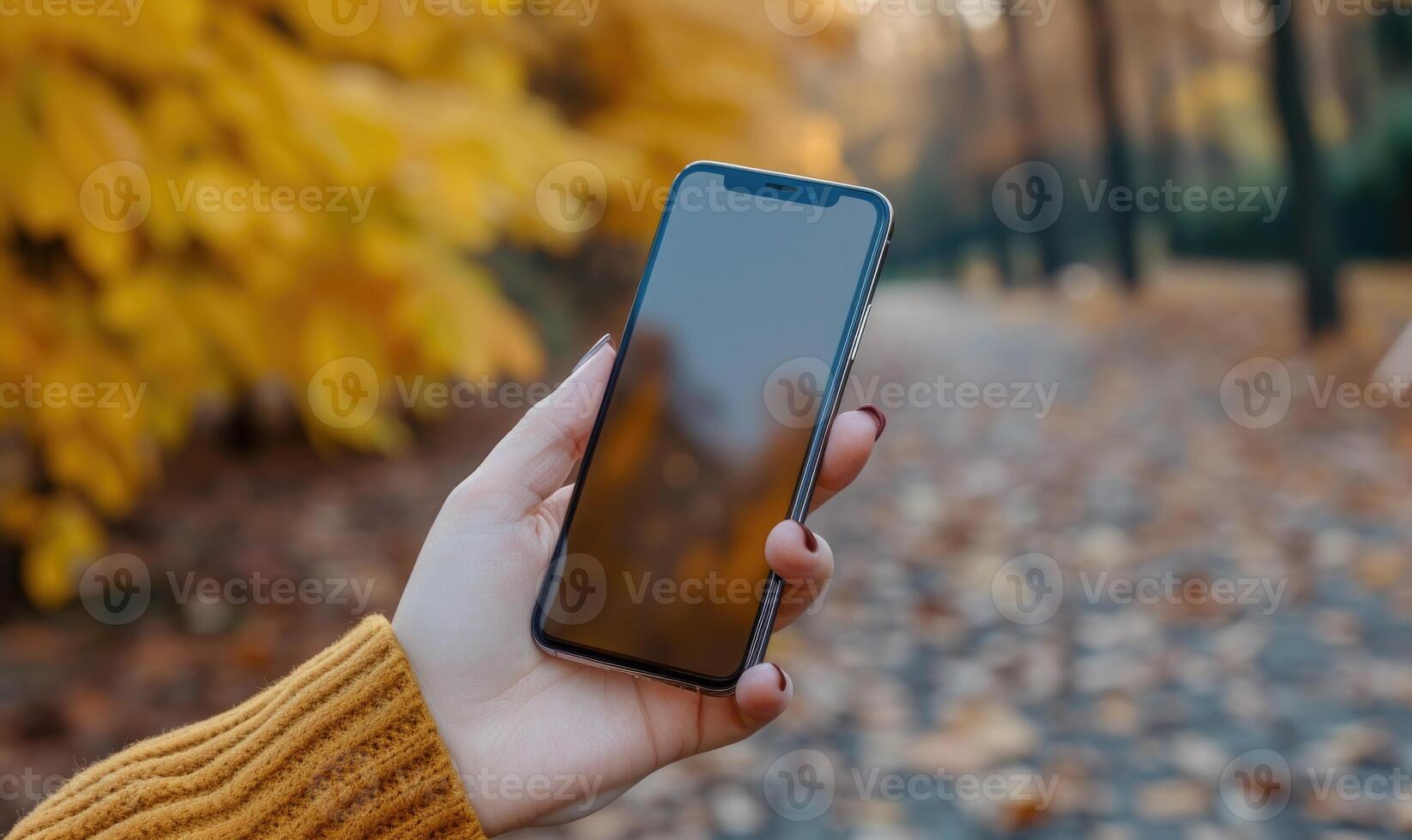 AI generated Female hand holding a smartphone with a blank screen on the background of the autumn park photo