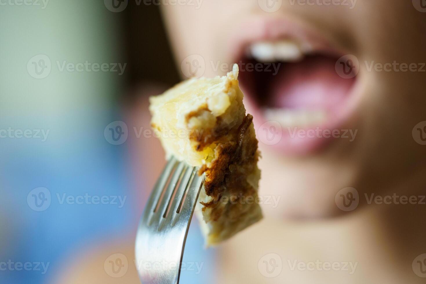 anónimo Adolescente niña acerca de a comer Fresco patata tortilla desde tenedor foto