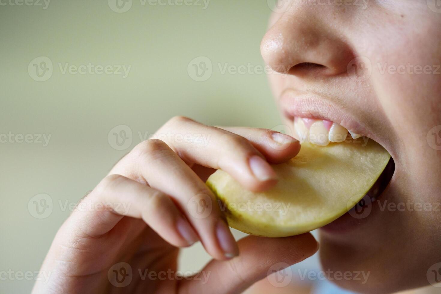 Anonymous teenage girl eating fresh apple slice photo