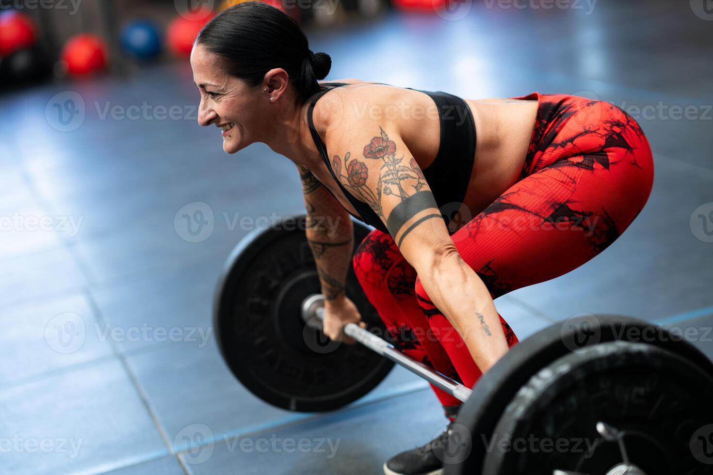 Smiling mature sportive woman weightlifting in a gym photo