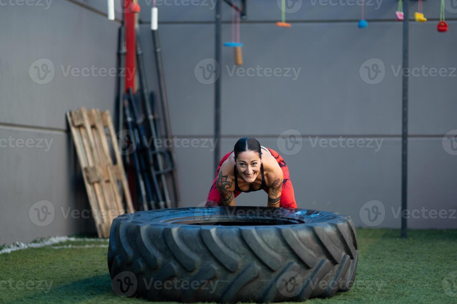 Sportive woman flipping a huge wheel in the gym photo