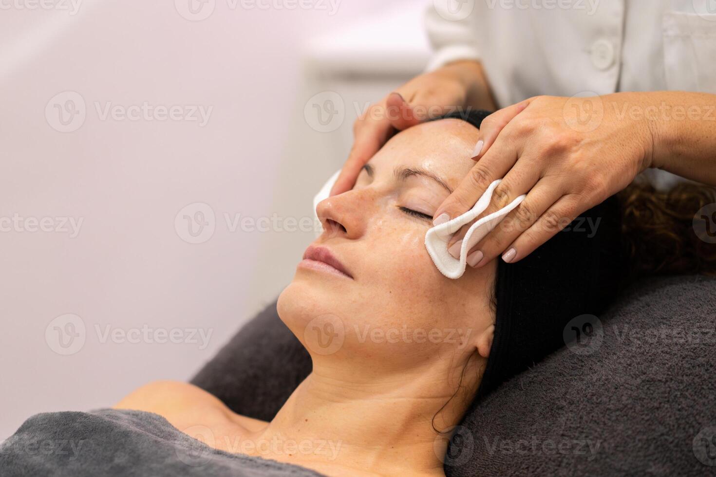 cosmetólogo quitando cara máscara con algodón almohadillas foto