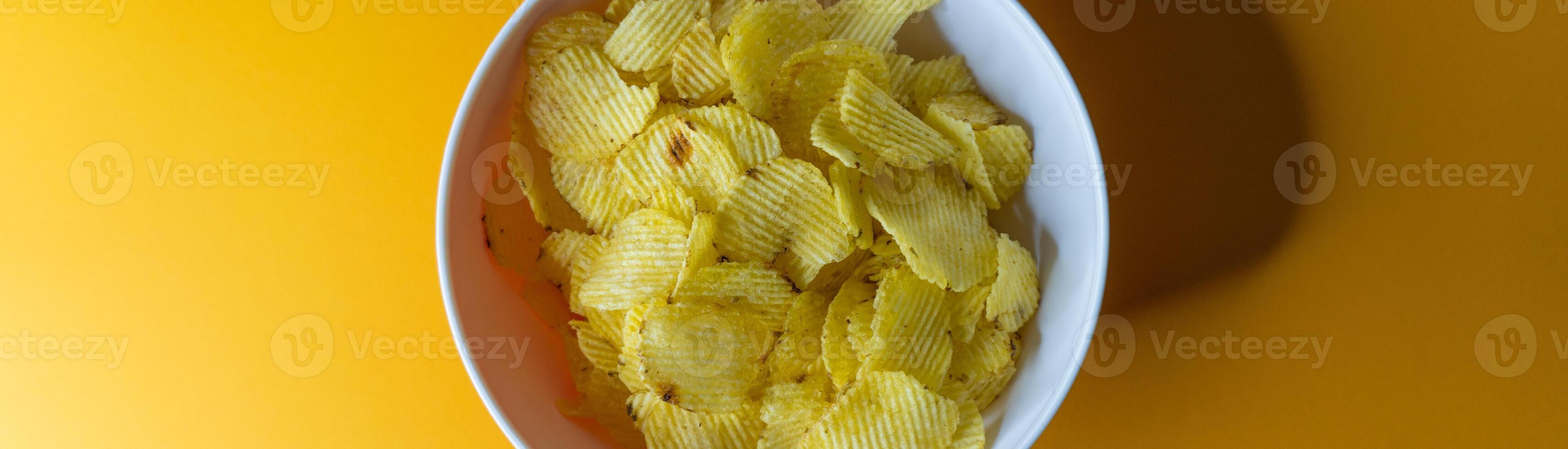 Close-up of potato chips or crisps in bowl against yellow background photo