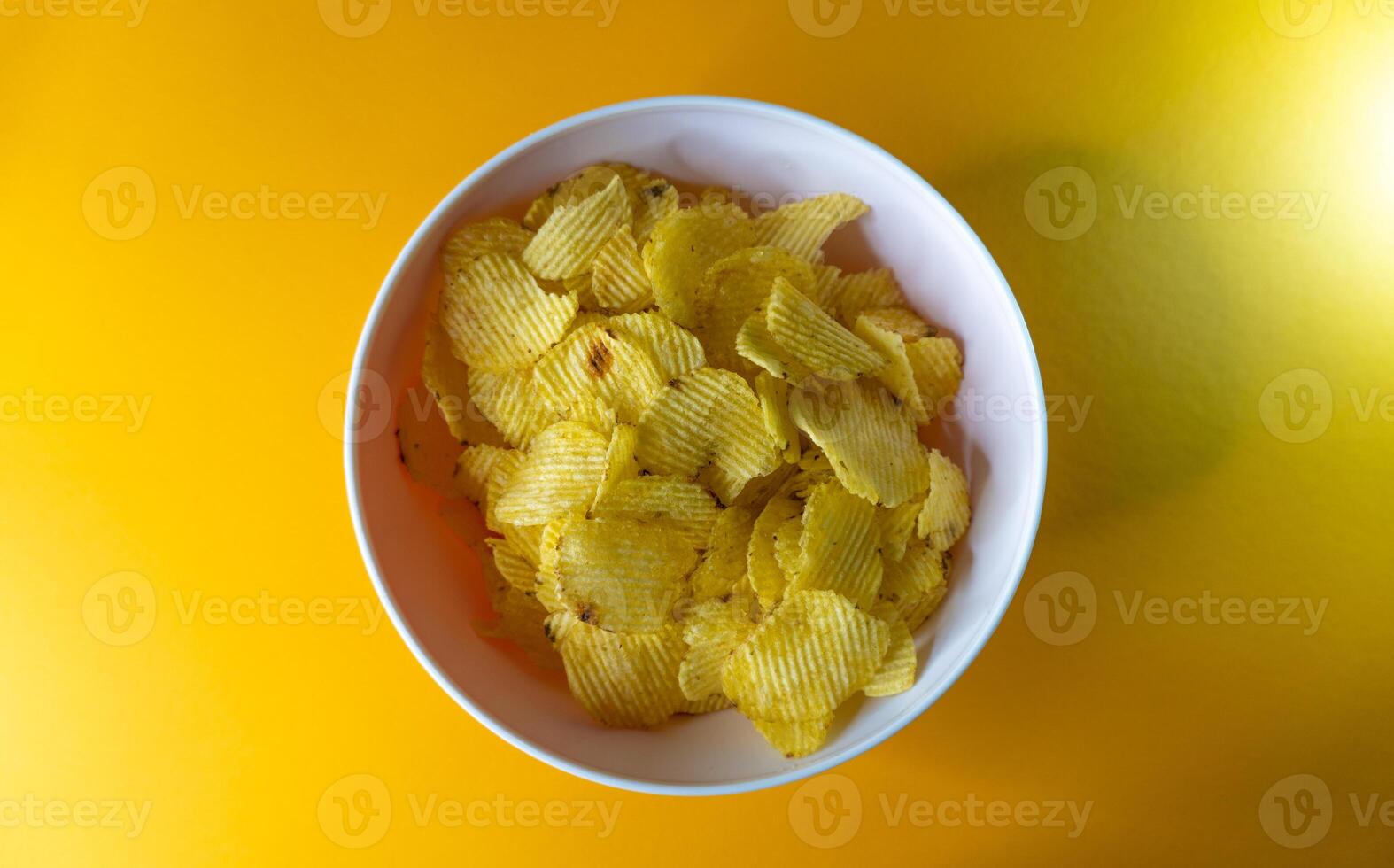 Close-up of potato chips or crisps in bowl against yellow background photo