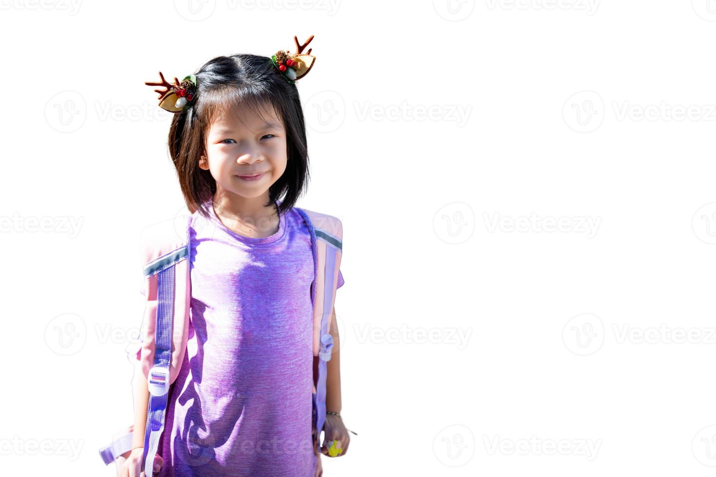 joven niña con reno cornamenta y que lleva un mochila, asiático alegre pequeño niño vistiendo púrpura ropa y reno cuerno pelo alfiler, aislado en un blanco antecedentes. foto