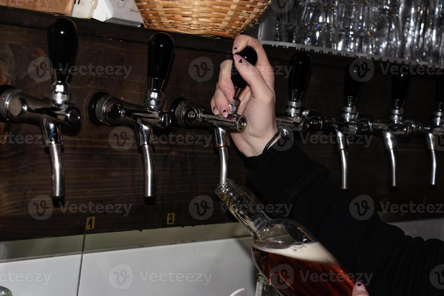 detrás el encimera. De las mujeres manos hermosamente y fácilmente verter cerveza dentro un botella. foto