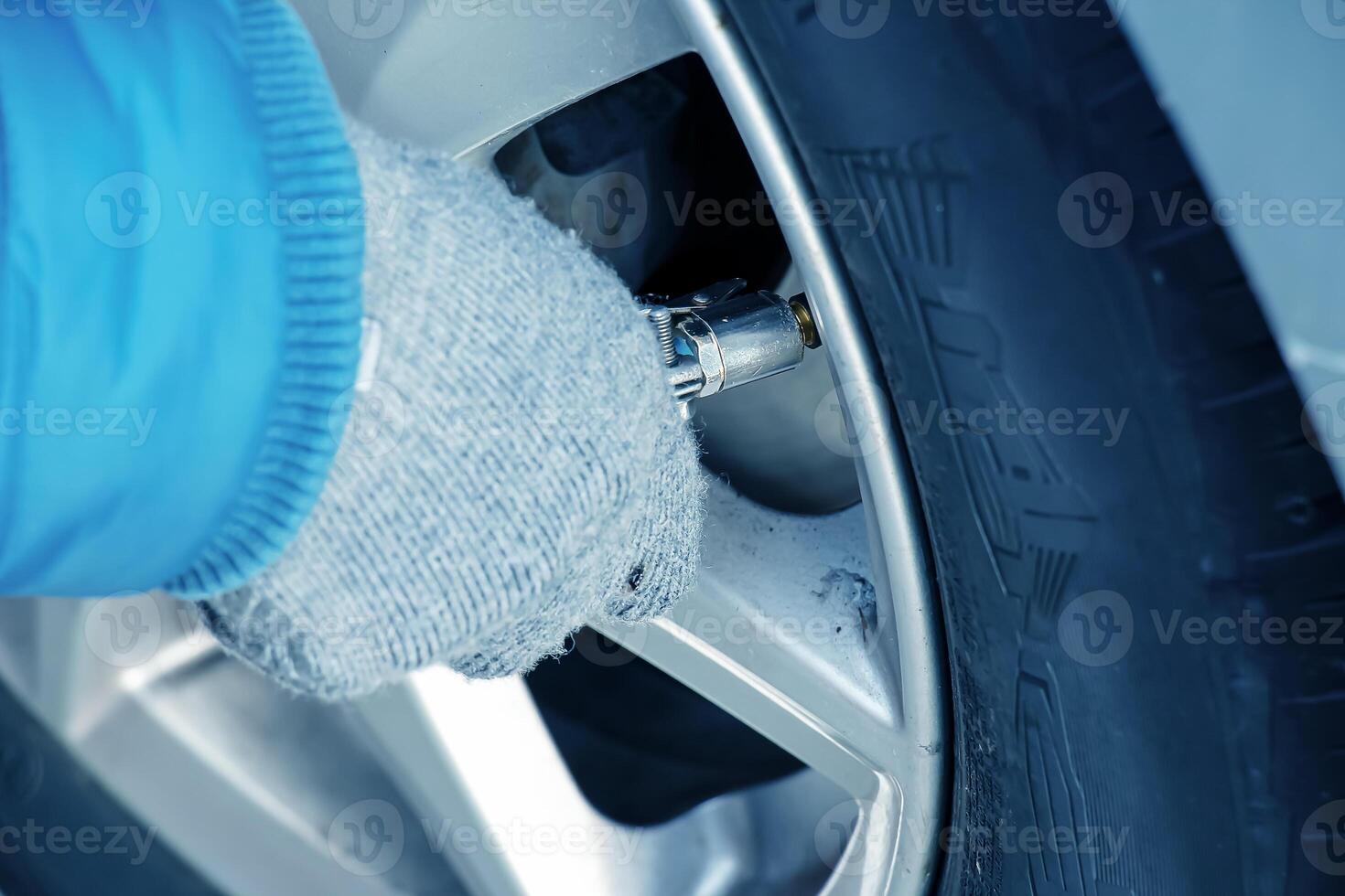 Hand holds the pressure gauge and fills the car tires with air. Car maintenance. photo