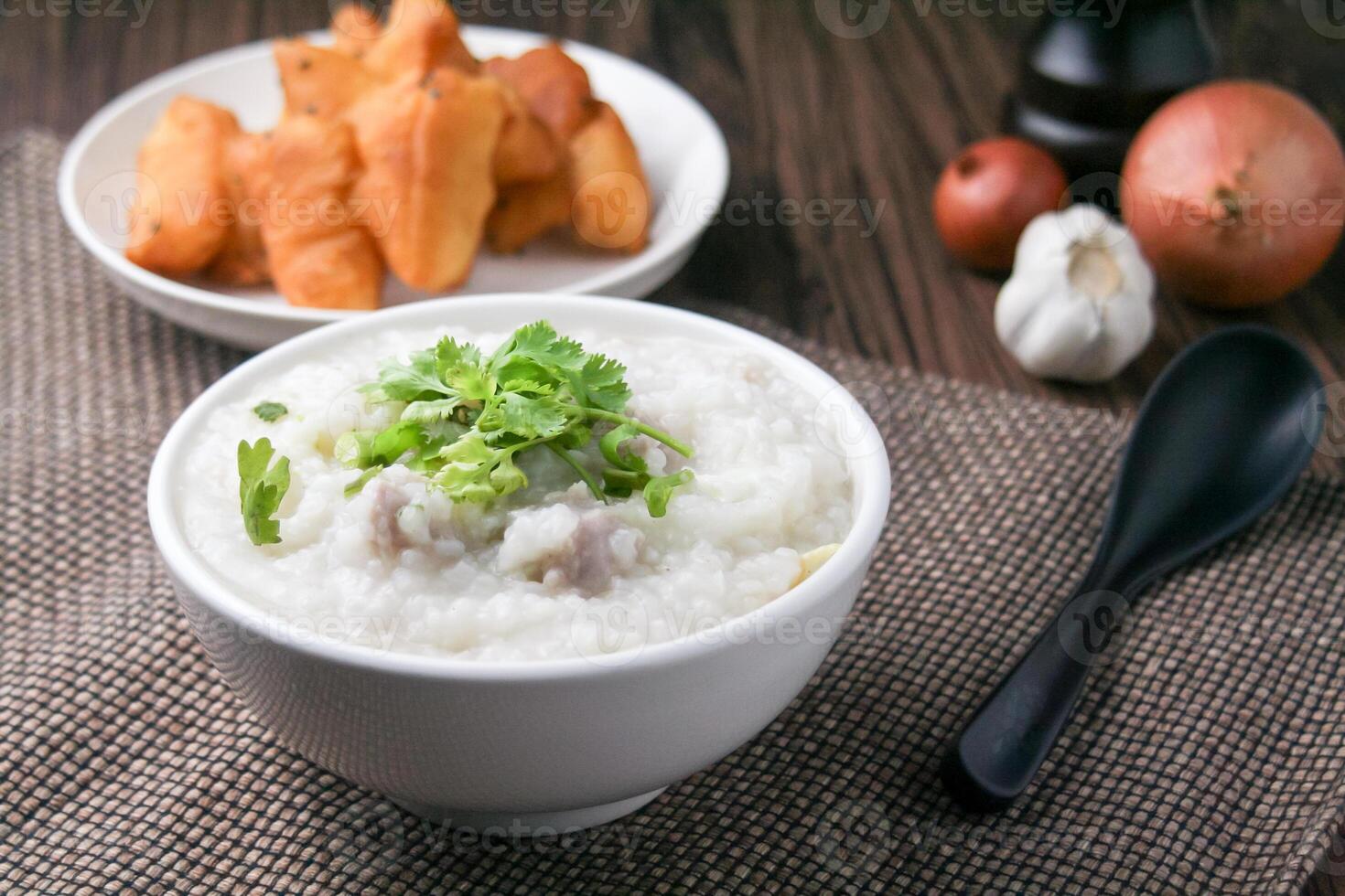 Pork porridge with coriander and ginger or porridge is similar to rice porridge but softer in texture. Served on a wooden table with patongko. For breakfast in the morning or evening photo