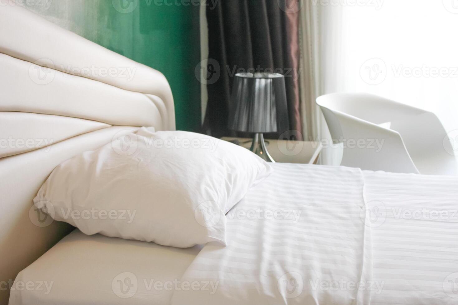 Interior of a hotel bedroom with white bed and white table lamp photo