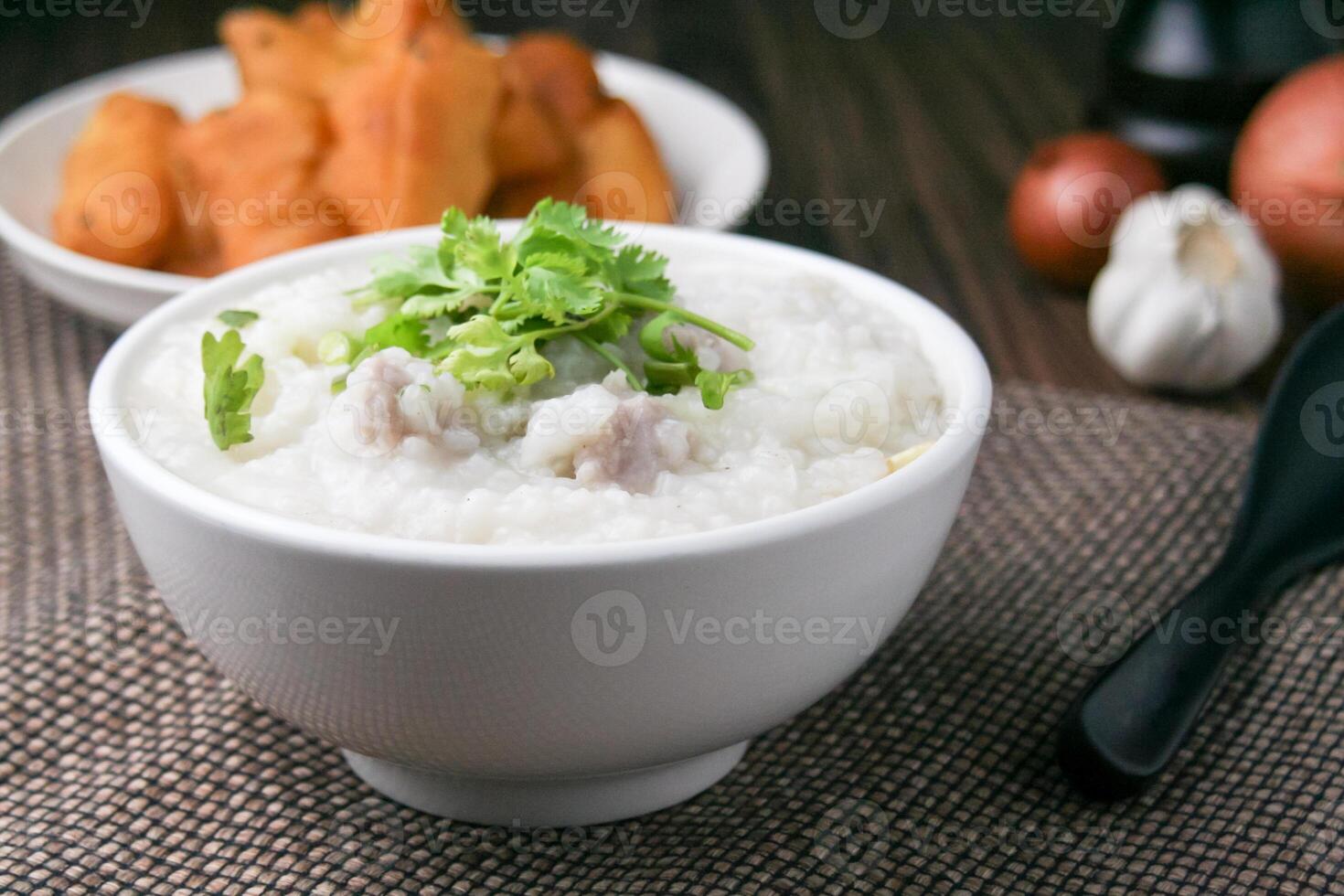 Pork porridge with coriander and ginger or porridge is similar to rice porridge but softer in texture. Served on a wooden table with patongko. For breakfast in the morning or evening photo