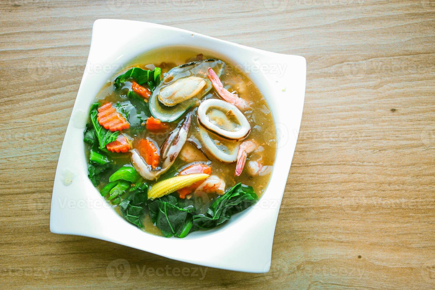 Wide Rice Noodles with Seafood in Gravy Sauce, or what we call Rad-Na Taley, served on a white plate in an Asian restaurant. photo