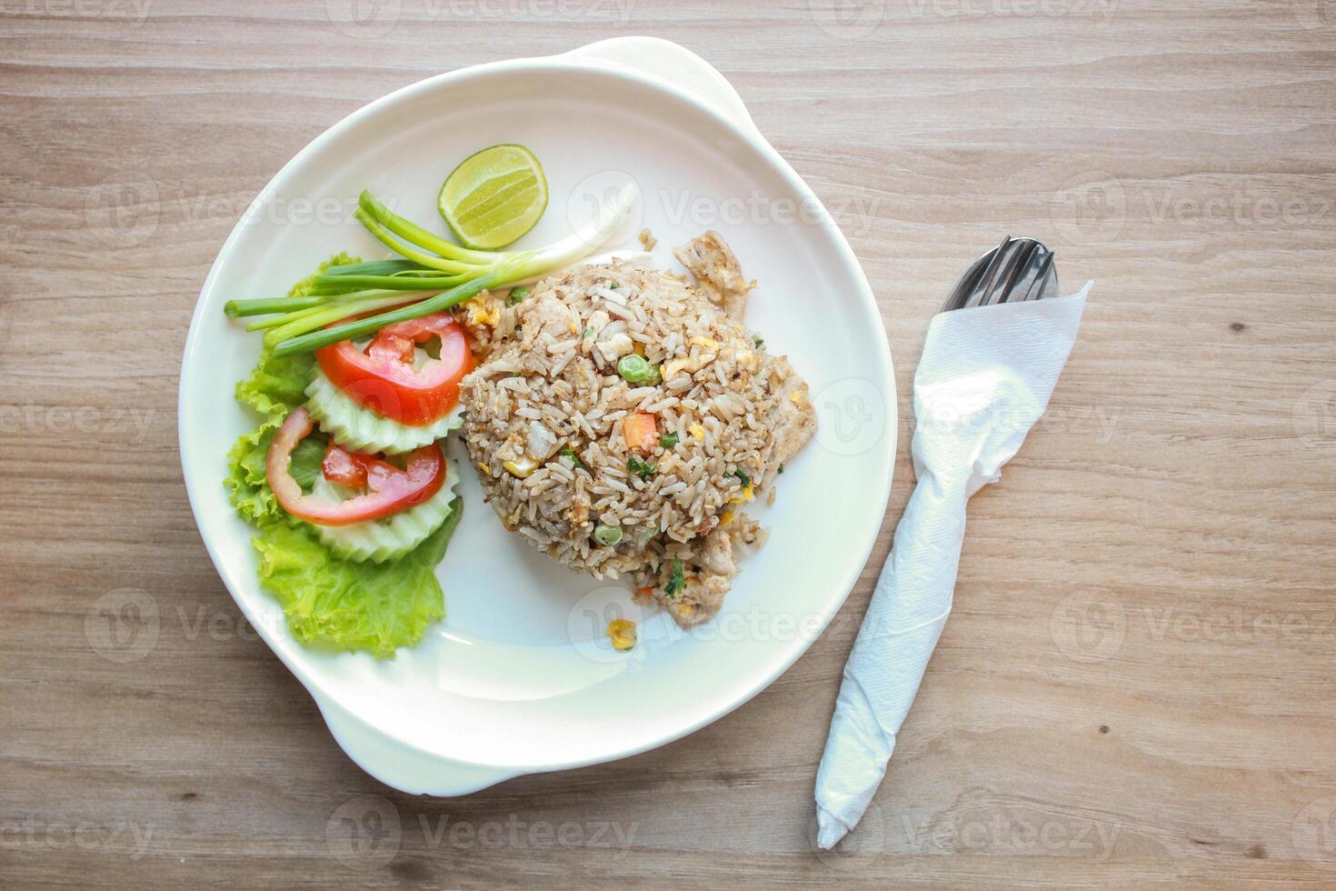 Pork fried rice served in a restaurant with wooden floor tables with tomatoes, cucumbers, scallions, fried rice, delicious food made from steamed rice. photo