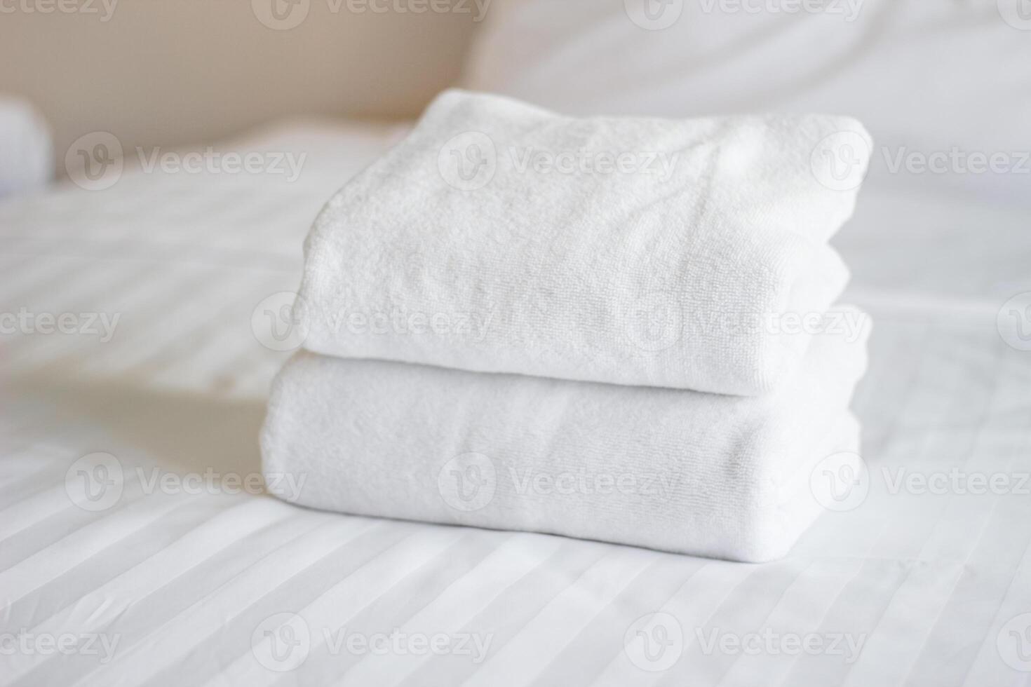 Stack of white towels on bed in hotel photo