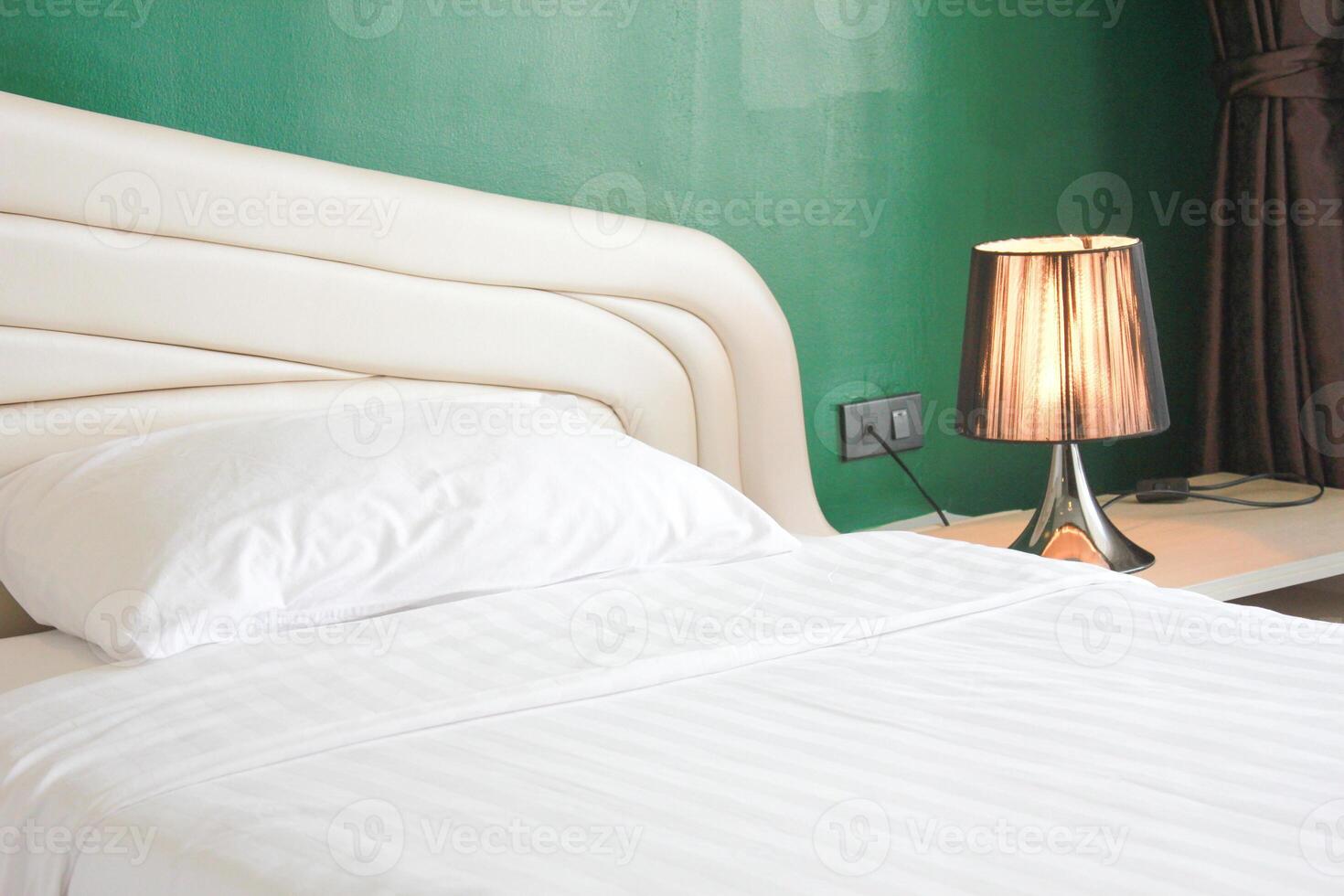 Interior of a hotel bedroom with white bed and white table lamp photo