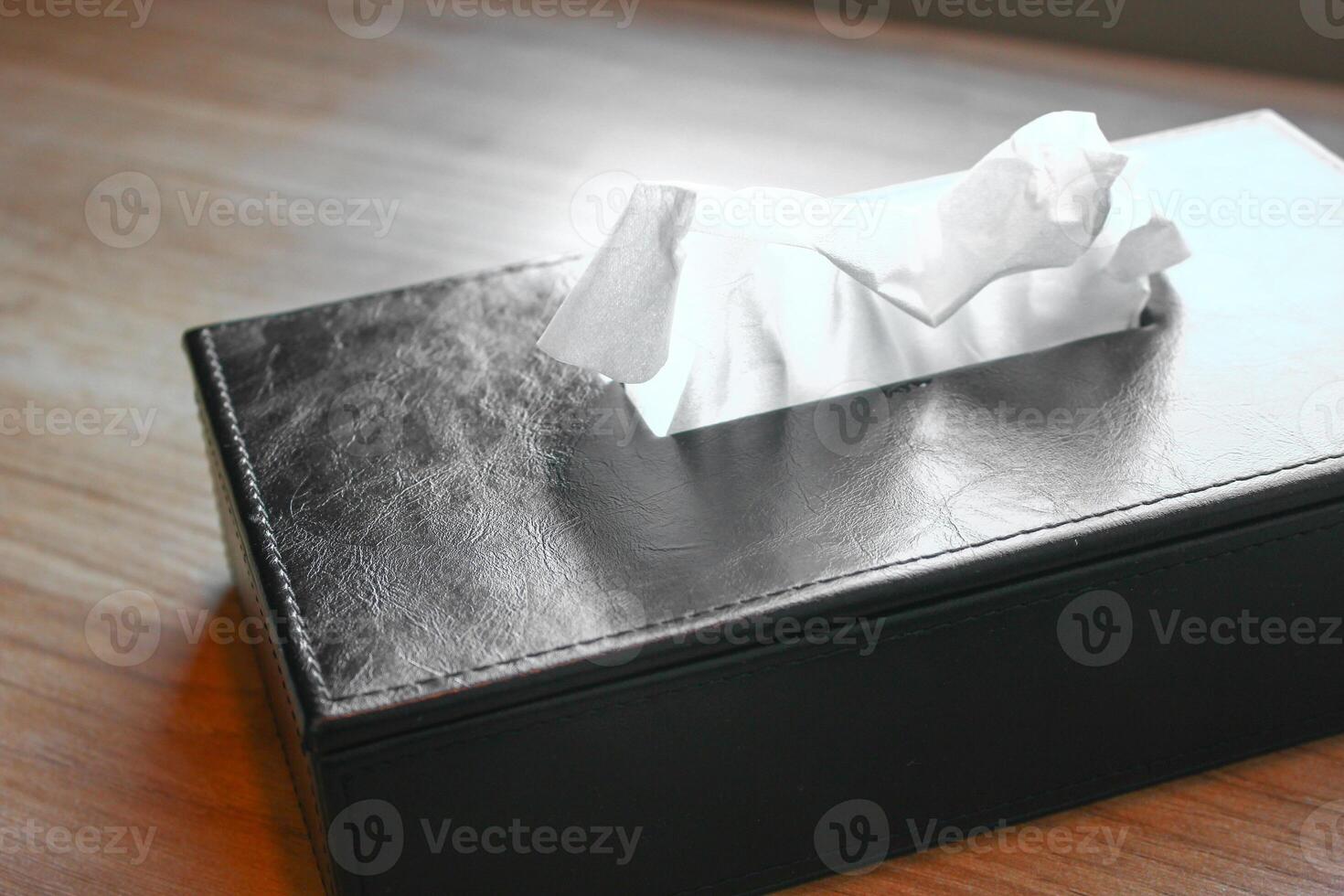 Crumpled napkin in a black leather case on a wooden table photo