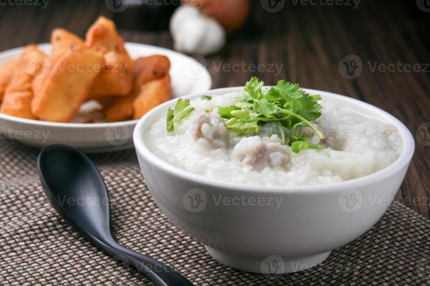 Pork porridge with coriander and ginger or porridge is similar to rice porridge but softer in texture. Served on a wooden table with patongko. For breakfast in the morning or evening photo