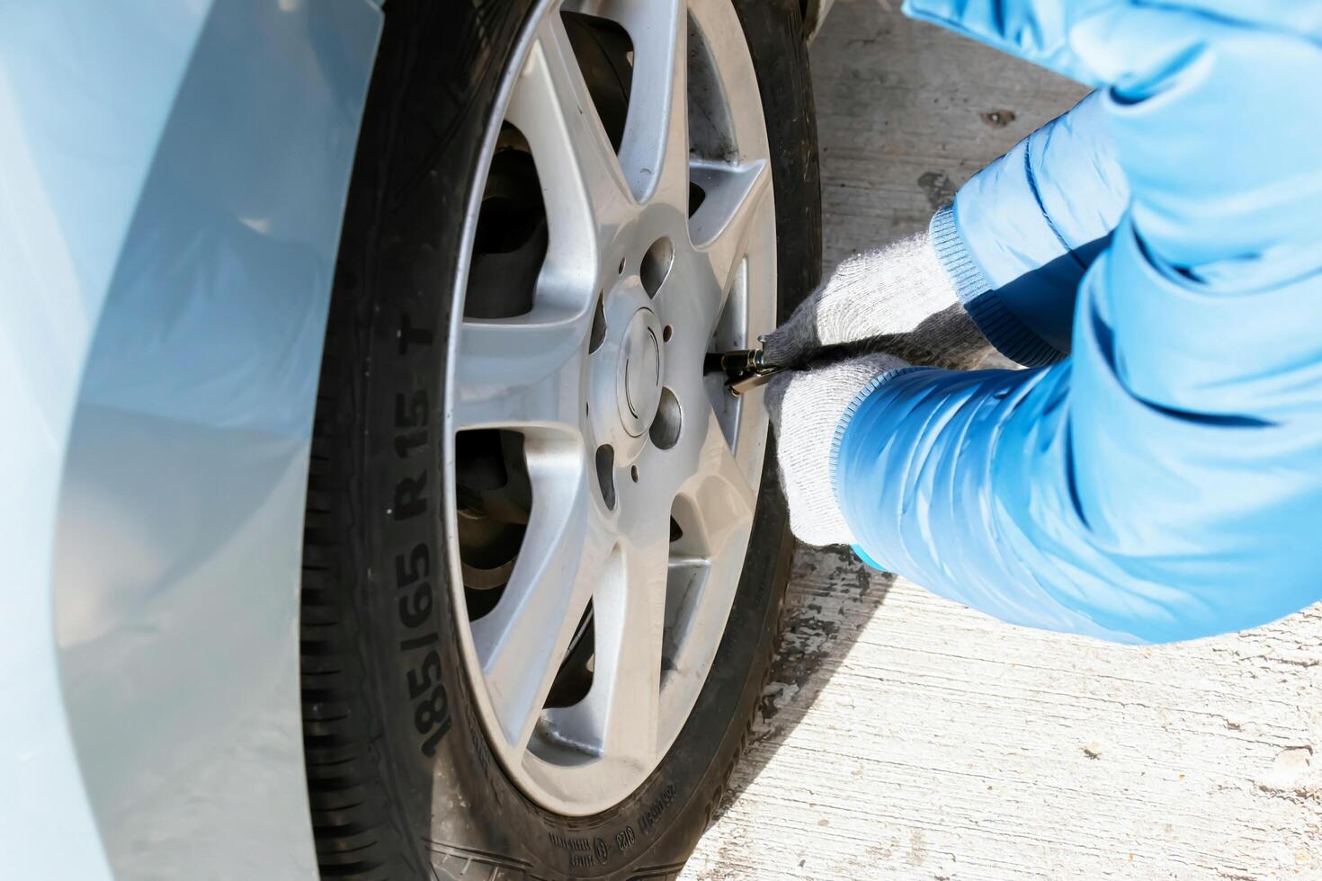 Hand holds the pressure gauge and fills the car tires with air. Car maintenance. photo