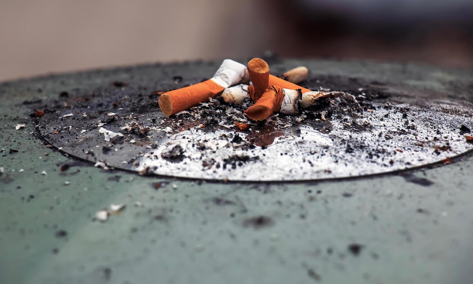 cenicero con cigarrillo campo de tiro al blanco y despojos mortales. anti-tabaco concepto. foto