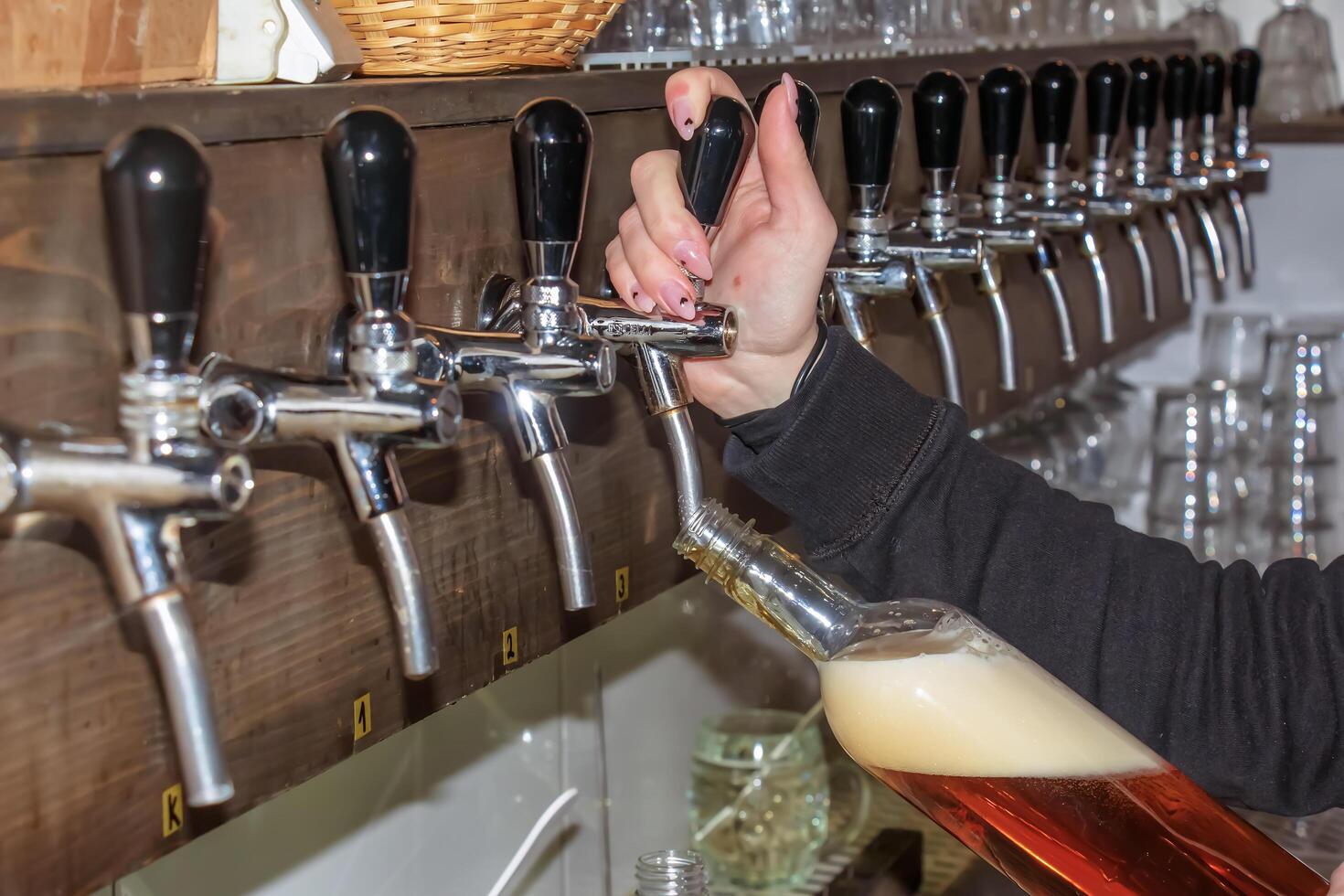 Behind the counter. Women's hands beautifully and easily pour beer into a bottle. photo