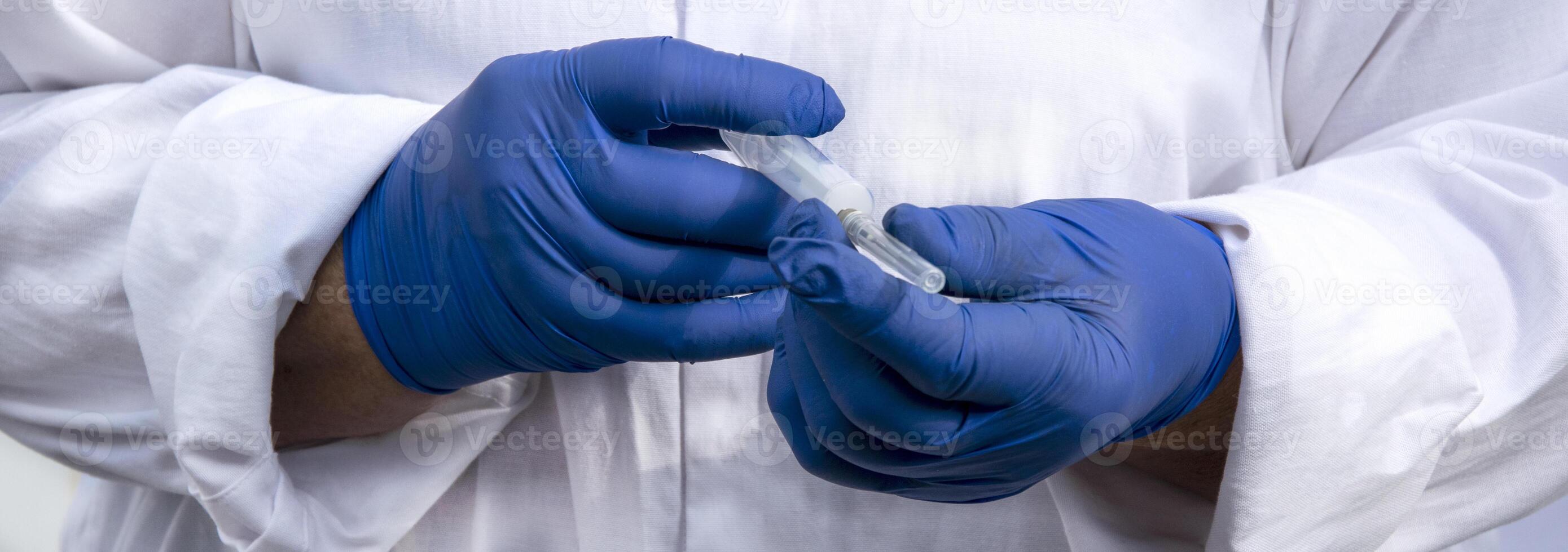 Hands in blue gloves with a syringe. photo