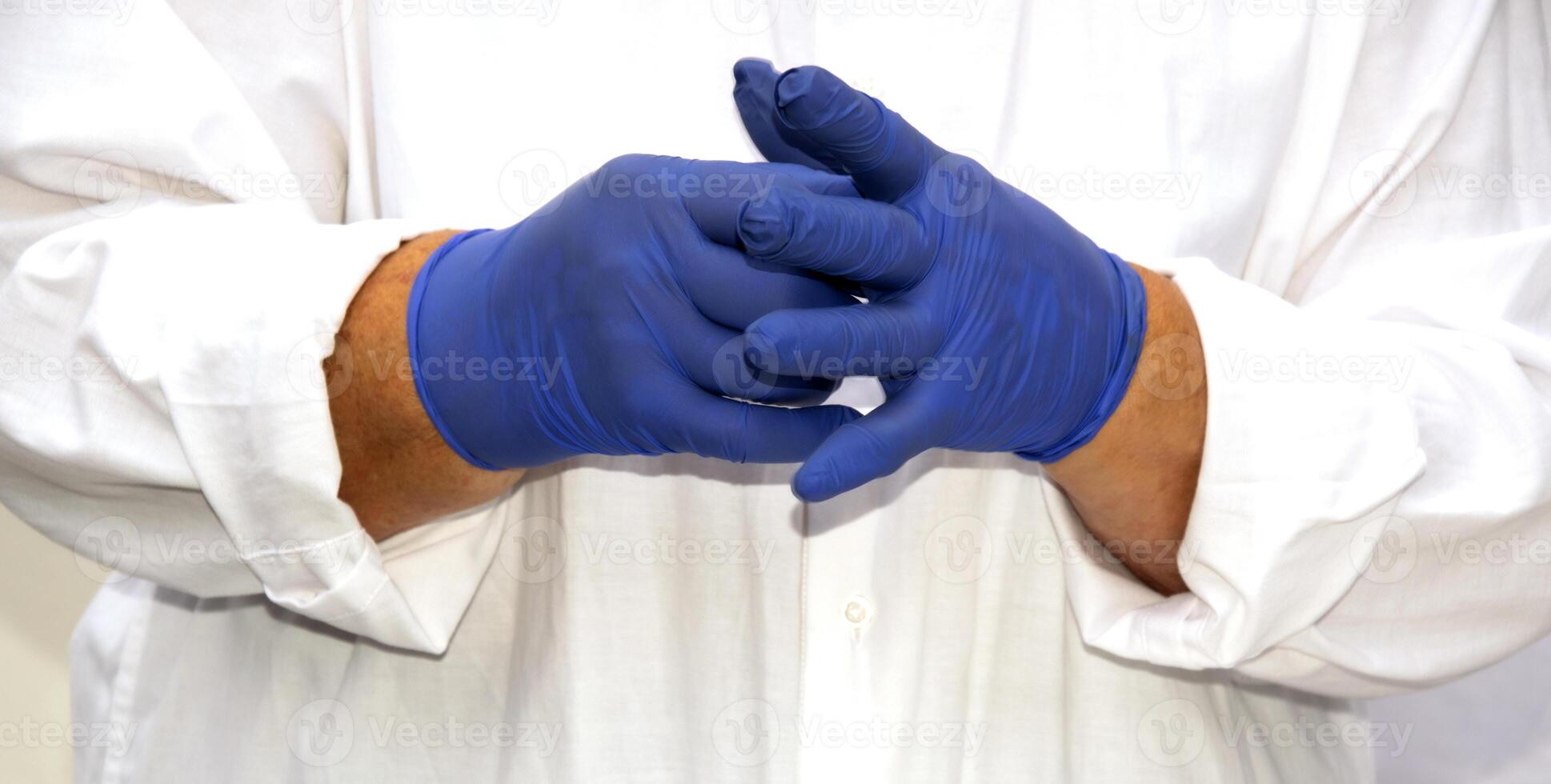 Medic hands in blue nitrile gloves. The doctor puts on sterile gloves against the background of a medical gown. photo