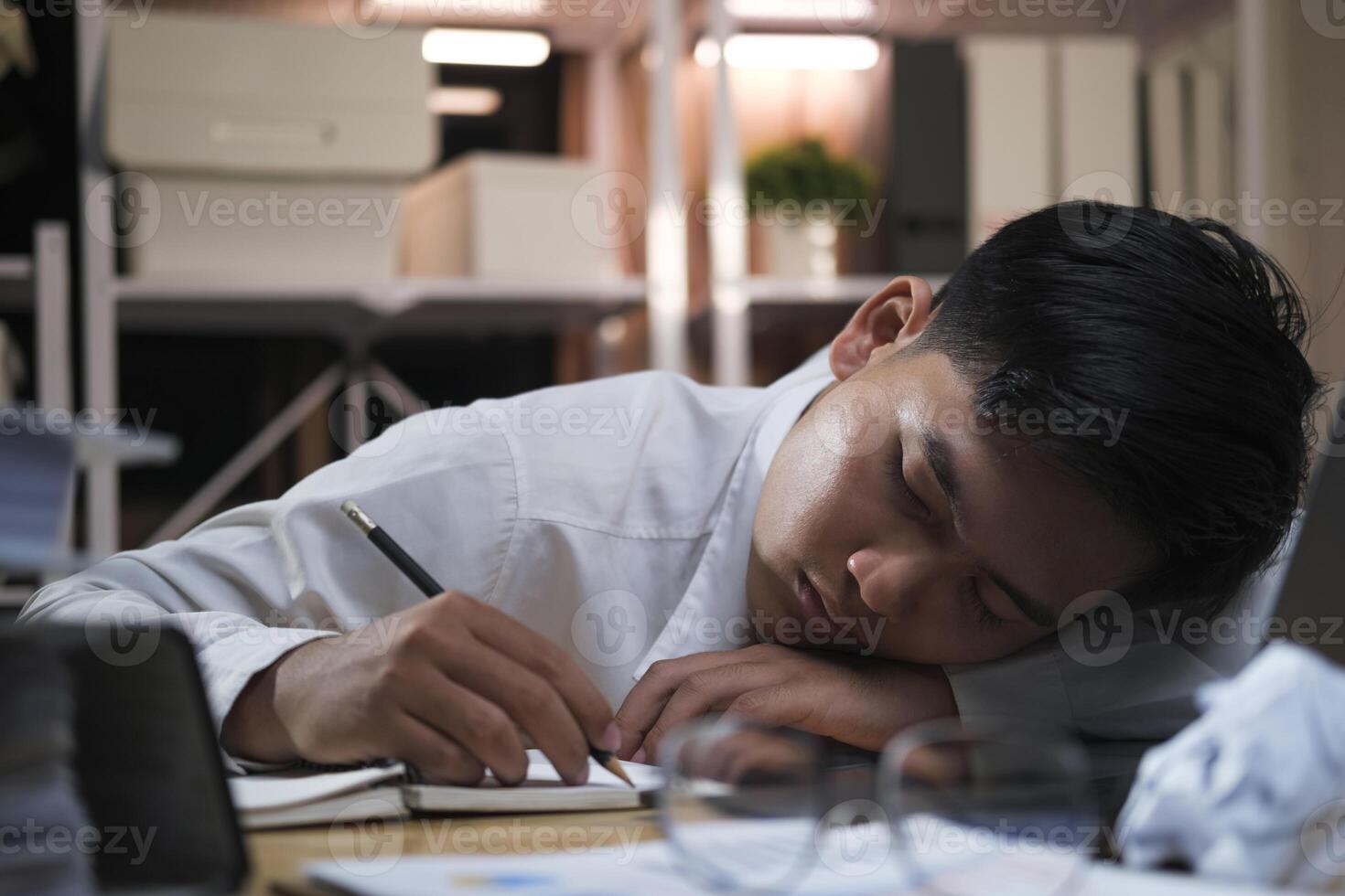 Young tired businessman lying on table at night office. photo
